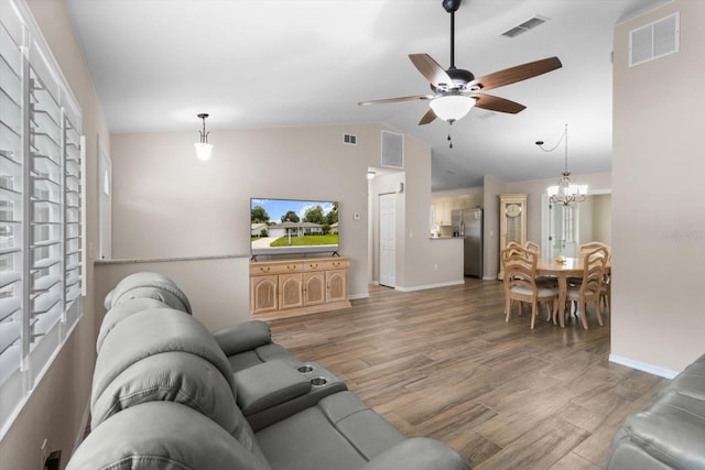 14481 SW 112th Cir, Dunnellon, FL 34432 - living room featuring ceiling fan, light wood-style floors, baseboards, vaulted ceiling, and a chandelier