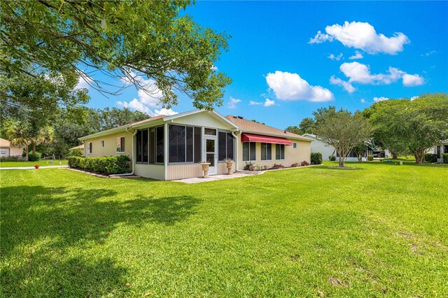 9891 SE 138th Loop, Summerfield, FL 34491 - rear view of house with a sunroom and a yard