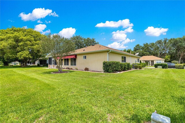 9891 SE 138th Loop, Summerfield, FL 34491 - view of side of home with stucco siding and a yard