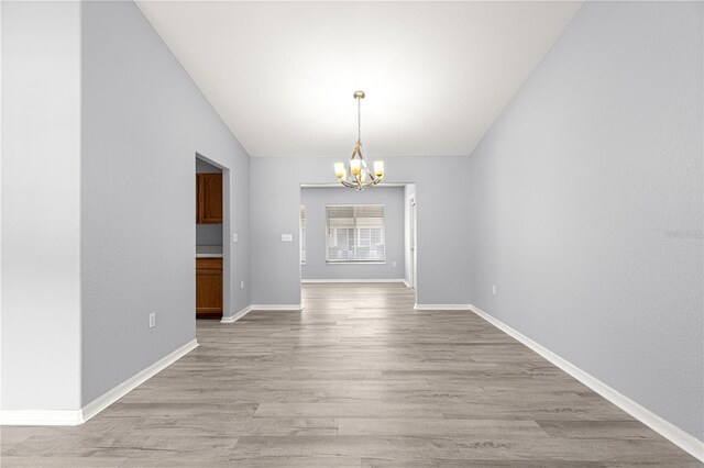 9891 SE 138th Loop, Summerfield, FL 34491 - unfurnished dining area with a chandelier, light wood finished floors, vaulted ceiling, and baseboards
