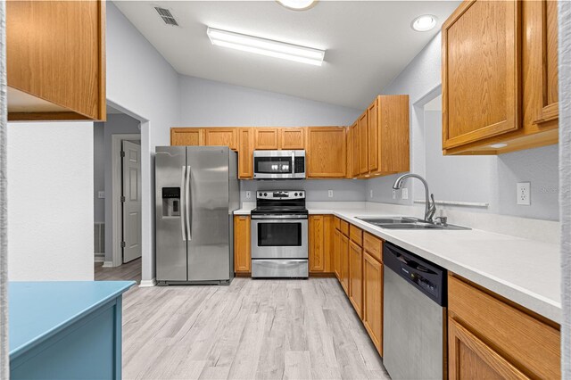 9891 SE 138th Loop, Summerfield, FL 34491 - kitchen featuring stainless steel appliances, a sink, vaulted ceiling, light wood finished floors, and light countertops