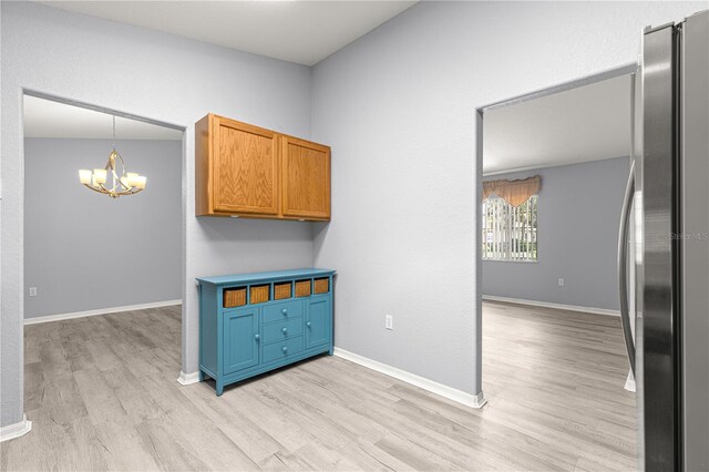 9891 SE 138th Loop, Summerfield, FL 34491 - kitchen with freestanding refrigerator, a chandelier, light wood-style flooring, baseboards, and decorative light fixtures
