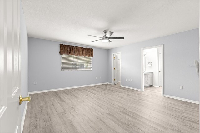 9891 SE 138th Loop, Summerfield, FL 34491 - unfurnished bedroom featuring light wood-style floors, baseboards, ensuite bathroom, ceiling fan, and a textured ceiling