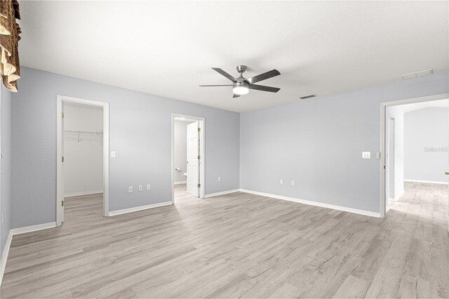 9891 SE 138th Loop, Summerfield, FL 34491 - unfurnished bedroom featuring a spacious closet, light wood finished floors, baseboards, and ceiling fan