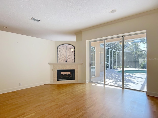 16 Ryewood Cir, Homosassa, FL 34446 - unfurnished living room featuring a sunroom, light wood finished floors, a textured ceiling, a tiled fireplace, and baseboards