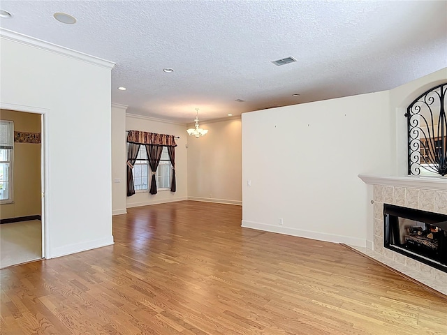 16 Ryewood Cir, Homosassa, FL 34446 - unfurnished living room featuring a textured ceiling, plenty of natural light, light wood-style flooring, ornamental molding, and a tiled fireplace