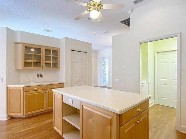 16 Ryewood Cir, Homosassa, FL 34446 - kitchen featuring light wood-style floors, light countertops, a kitchen island, ceiling fan, and a sink