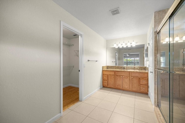 4225 SW 57th Ave, Ocala, FL 34474 - full bathroom featuring vanity, a stall shower, a spacious closet, baseboards, and tile patterned flooring