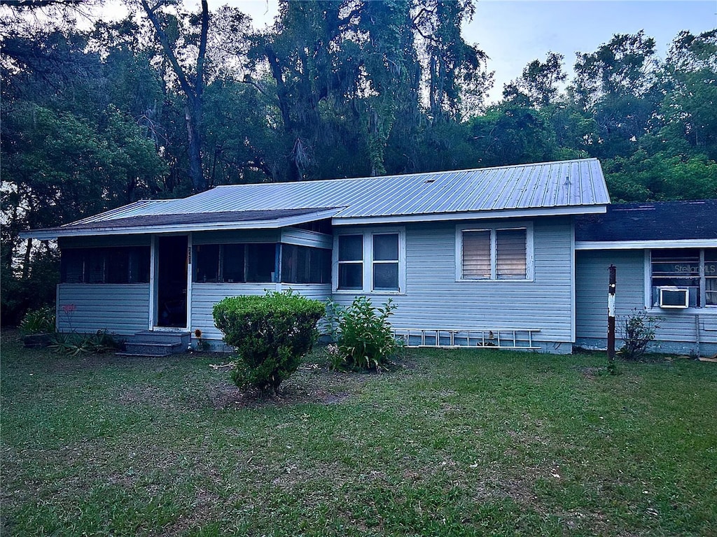 2409 NW 7th St, Ocala, FL 34475 - view of front of property featuring a front yard, a sunroom, entry steps, metal roof, and cooling unit
