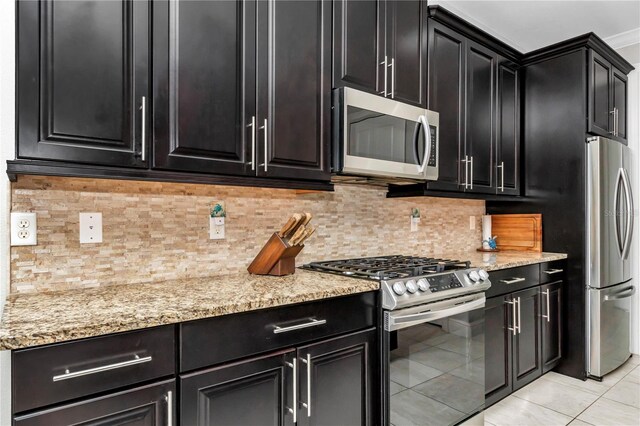 7210 SW 179th Ct, Dunnellon, FL 34432 - kitchen featuring appliances with stainless steel finishes, dark cabinets, light tile patterned flooring, and light stone countertops