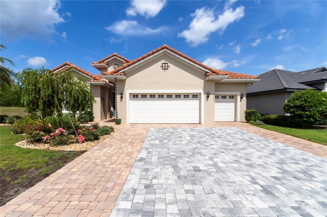 7210 SW 179th Ct, Dunnellon, FL 34432 - mediterranean / spanish-style house with an attached garage, decorative driveway, a tiled roof, and stucco siding