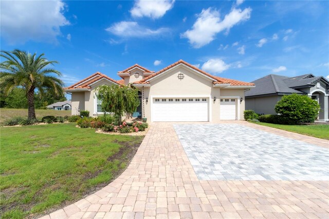 7210 SW 179th Ct, Dunnellon, FL 34432 - mediterranean / spanish house featuring decorative driveway, stucco siding, a garage, a front lawn, and a tile roof