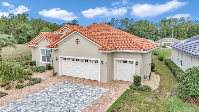 7210 SW 179th Ct, Dunnellon, FL 34432 - mediterranean / spanish-style home featuring an attached garage, decorative driveway, a tiled roof, and stucco siding