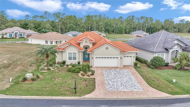 7210 SW 179th Ct, Dunnellon, FL 34432 - mediterranean / spanish house with a tiled roof, a garage, stucco siding, decorative driveway, and a front yard