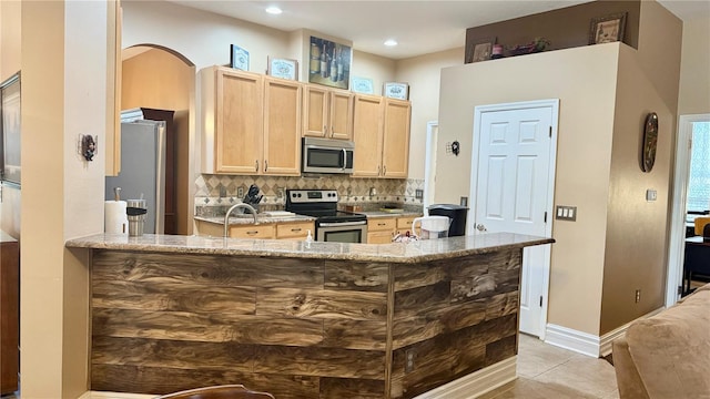 1138 Lumsden Trace Cir, Valrico, FL 33594 - kitchen featuring stainless steel appliances, light brown cabinetry, decorative backsplash, light stone countertops, and baseboards