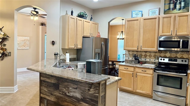 1138 Lumsden Trace Cir, Valrico, FL 33594 - kitchen featuring stainless steel appliances, arched walkways, light brown cabinetry, and backsplash