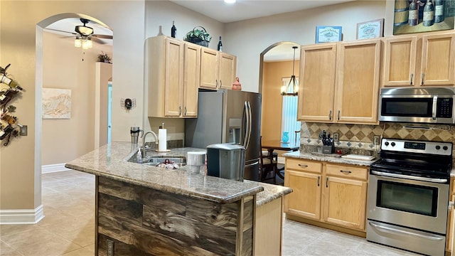1138 Lumsden Trace Cir, Valrico, FL 33594 - kitchen with stainless steel appliances, arched walkways, light brown cabinets, a sink, and a peninsula