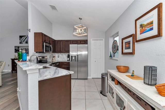 16969 SW 40th Cir, Ocala, FL 34473 - kitchen featuring appliances with stainless steel finishes, vaulted ceiling, a peninsula, a sink, and pendant lighting