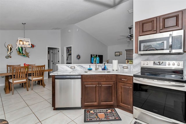 16969 SW 40th Cir, Ocala, FL 34473 - kitchen featuring appliances with stainless steel finishes, lofted ceiling, a sink, a peninsula, and light tile patterned floors