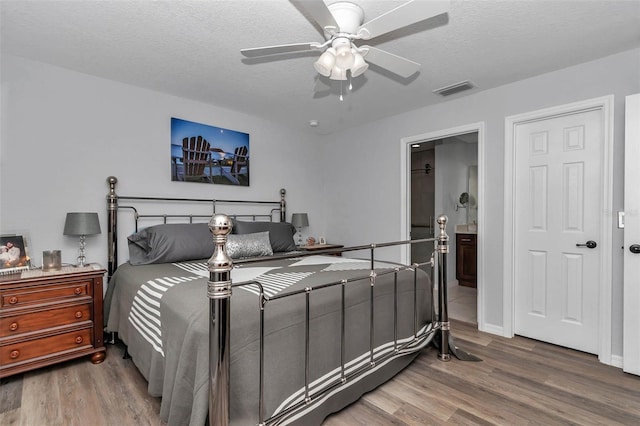 16969 SW 40th Cir, Ocala, FL 34473 - bedroom featuring wood finished floors, ensuite bathroom, a textured ceiling, and a ceiling fan