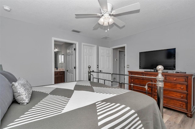 16969 SW 40th Cir, Ocala, FL 34473 - bedroom featuring light wood-type flooring, connected bathroom, ceiling fan, and a textured ceiling
