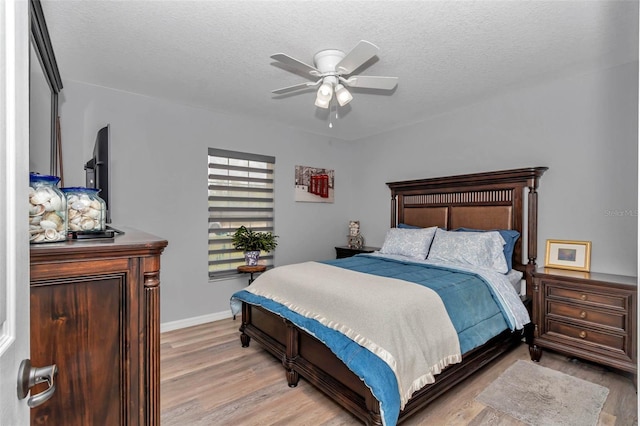 16969 SW 40th Cir, Ocala, FL 34473 - bedroom with light wood finished floors, a textured ceiling, baseboards, and ceiling fan