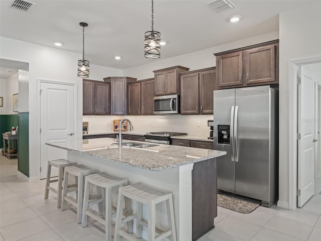 7206 SW 60th Ln, Ocala, FL 34474 - kitchen featuring appliances with stainless steel finishes, a sink, dark brown cabinetry, hanging light fixtures, and light stone counters