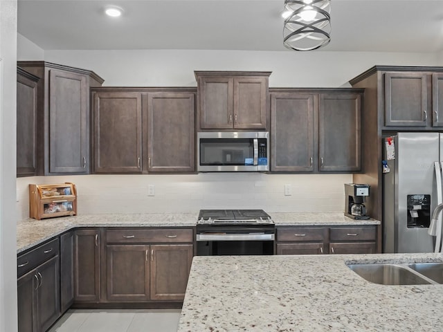 7206 SW 60th Ln, Ocala, FL 34474 - kitchen with stainless steel appliances, dark brown cabinetry, a sink, light stone countertops, and backsplash
