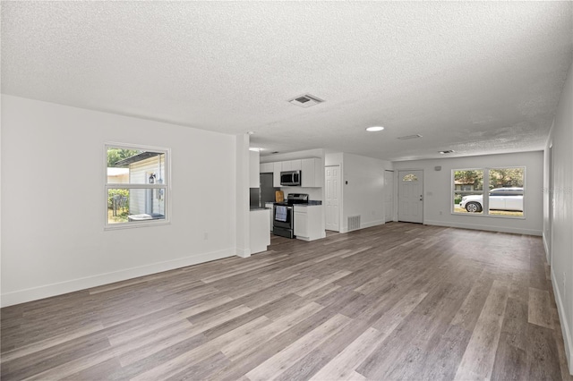 4095 SW 144th St, Ocala, FL 34473 - unfurnished living room with a textured ceiling, light wood finished floors, and baseboards