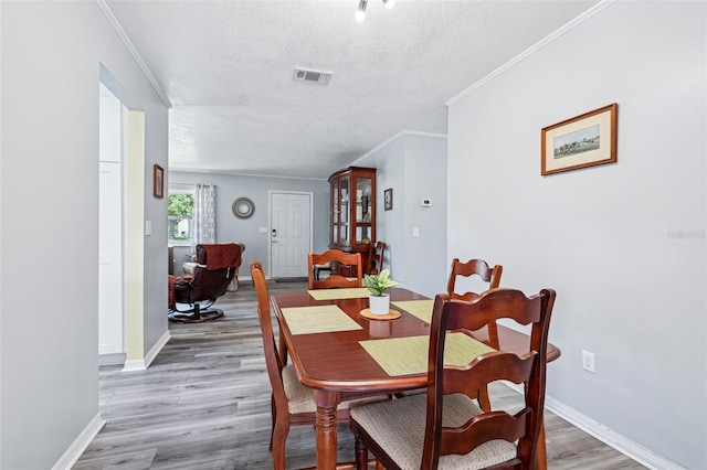 6448 SW 111th Pl, Ocala, FL 34476 - dining space with a textured ceiling, light wood finished floors, crown molding, and baseboards