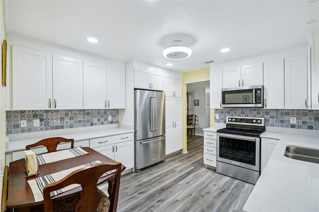 6448 SW 111th Pl, Ocala, FL 34476 - kitchen featuring appliances with stainless steel finishes, light countertops, light wood-style flooring, white cabinetry, and recessed lighting