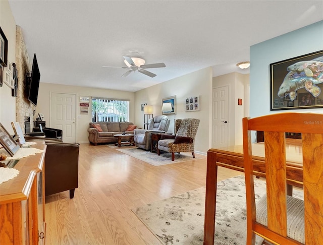 8785 SW 93rd Ln Unit C, Ocala, FL 34481 - living area featuring light wood-type flooring, a ceiling fan, a stone fireplace, and baseboards