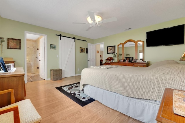 8785 SW 93rd Ln Unit C, Ocala, FL 34481 - bedroom featuring a barn door, wood finished floors, ceiling fan, and baseboards