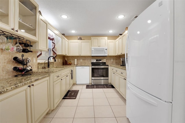 8785 SW 93rd Ln Unit C, Ocala, FL 34481 - kitchen featuring white appliances, a sink, cream cabinets, decorative backsplash, and recessed lighting