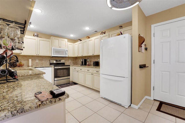 8785 SW 93rd Ln Unit C, Ocala, FL 34481 - kitchen featuring white appliances, light tile patterned floors, backsplash, light stone countertops, and recessed lighting