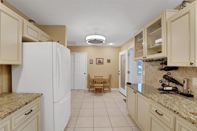 8785 SW 93rd Ln Unit C, Ocala, FL 34481 - kitchen featuring cream cabinets, freestanding refrigerator, light tile patterned floors, and a textured ceiling