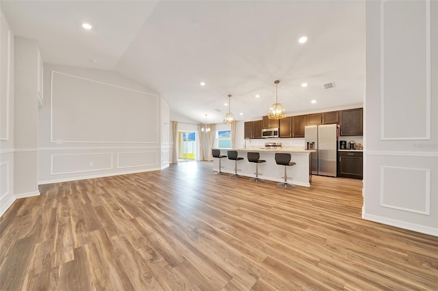 8943 SE 41st Court Rd, Ocala, FL 34480 - kitchen with stainless steel appliances, open floor plan, light countertops, a breakfast bar area, and vaulted ceiling