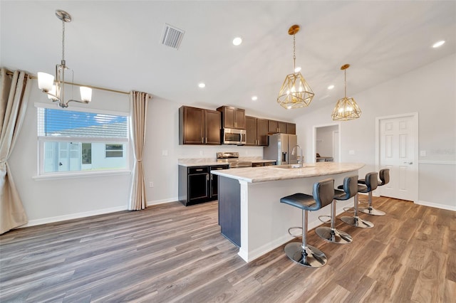 8943 SE 41st Court Rd, Ocala, FL 34480 - kitchen with appliances with stainless steel finishes, a chandelier, light wood-type flooring, a breakfast bar area, and a kitchen island with sink