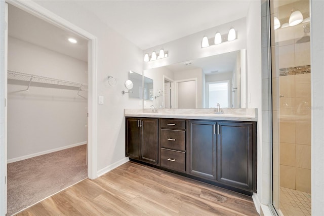 8943 SE 41st Court Rd, Ocala, FL 34480 - bathroom with wood finished floors, a stall shower, double vanity, a walk in closet, and baseboards