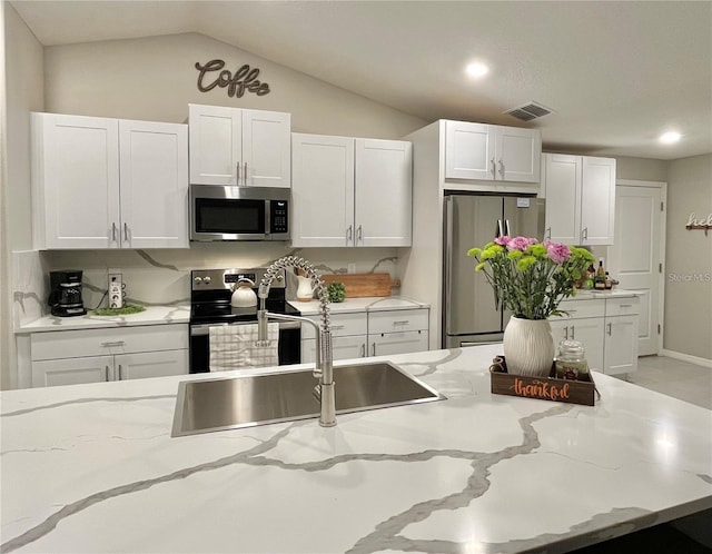 5667 SW 92nd Pl, Ocala, FL 34476 - kitchen with appliances with stainless steel finishes, a sink, white cabinets, light stone countertops, and vaulted ceiling