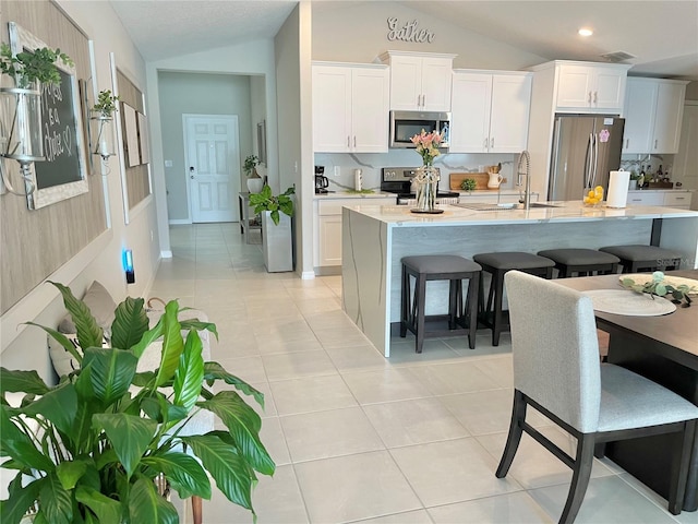 5667 SW 92nd Pl, Ocala, FL 34476 - kitchen featuring appliances with stainless steel finishes, lofted ceiling, a kitchen island with sink, a kitchen breakfast bar, and light countertops