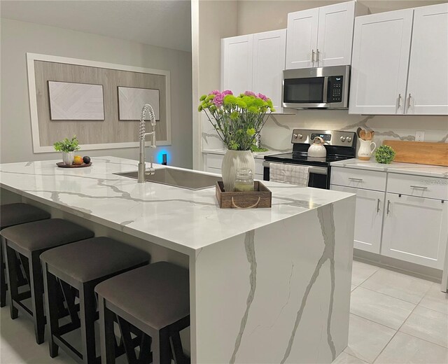 5667 SW 92nd Pl, Ocala, FL 34476 - kitchen with stainless steel appliances, a sink, white cabinetry, and a kitchen island with sink