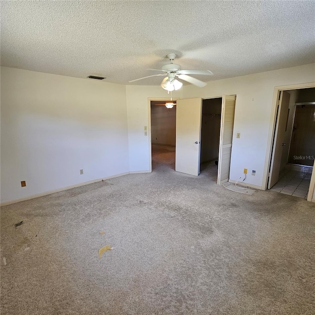 8635 SW 95th St Unit G, Ocala, FL 34481 - unfurnished bedroom with carpet flooring, baseboards, a textured ceiling, connected bathroom, and ceiling fan