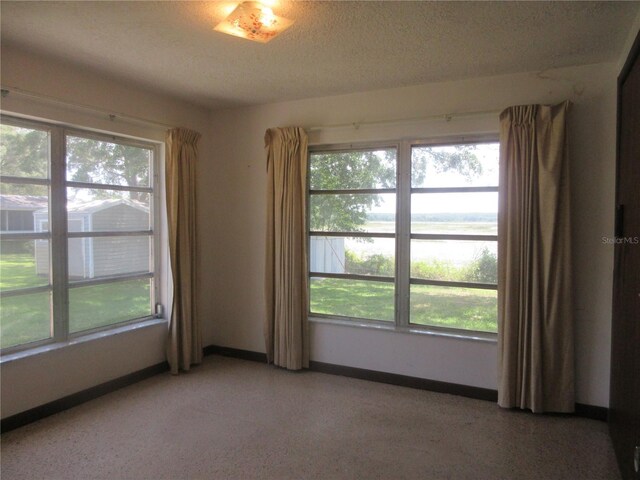 1675 SE 190th Ave, Silver Springs, FL 34488 - spare room featuring a water view, healthy amount of natural light, baseboards, and a textured ceiling