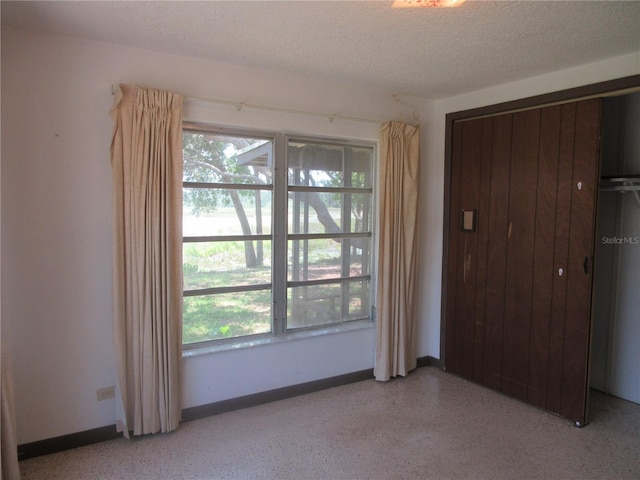 1675 SE 190th Ave, Silver Springs, FL 34488 - unfurnished bedroom featuring baseboards, a textured ceiling, dark speckled floor, and a closet
