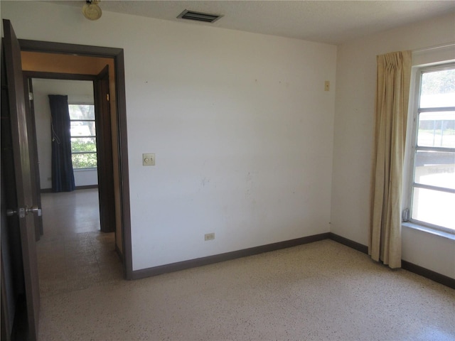 1675 SE 190th Ave, Silver Springs, FL 34488 - unfurnished room featuring healthy amount of natural light, baseboards, and dark aggregate flooring