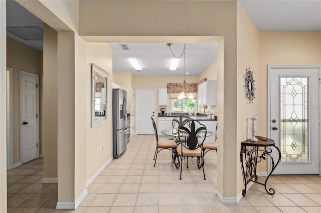 9408 SE 132nd Loop, Summerfield, FL 34491 - kitchen featuring stainless steel refrigerator with ice dispenser, white cabinets, dark countertops, light tile patterned floors, and a textured wall