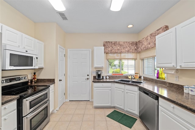 9408 SE 132nd Loop, Summerfield, FL 34491 - kitchen featuring stainless steel appliances, a sink, dark countertops, white cabinetry, and a textured ceiling