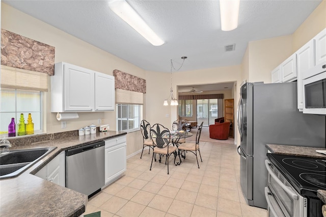 9408 SE 132nd Loop, Summerfield, FL 34491 - kitchen featuring stainless steel appliances, dark countertops, a sink, white cabinetry, and a textured ceiling