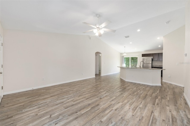 5425 Pecan Rd, Ocala, FL 34472 - unfurnished living room with arched walkways, light wood-style flooring, ceiling fan, vaulted ceiling, and baseboards
